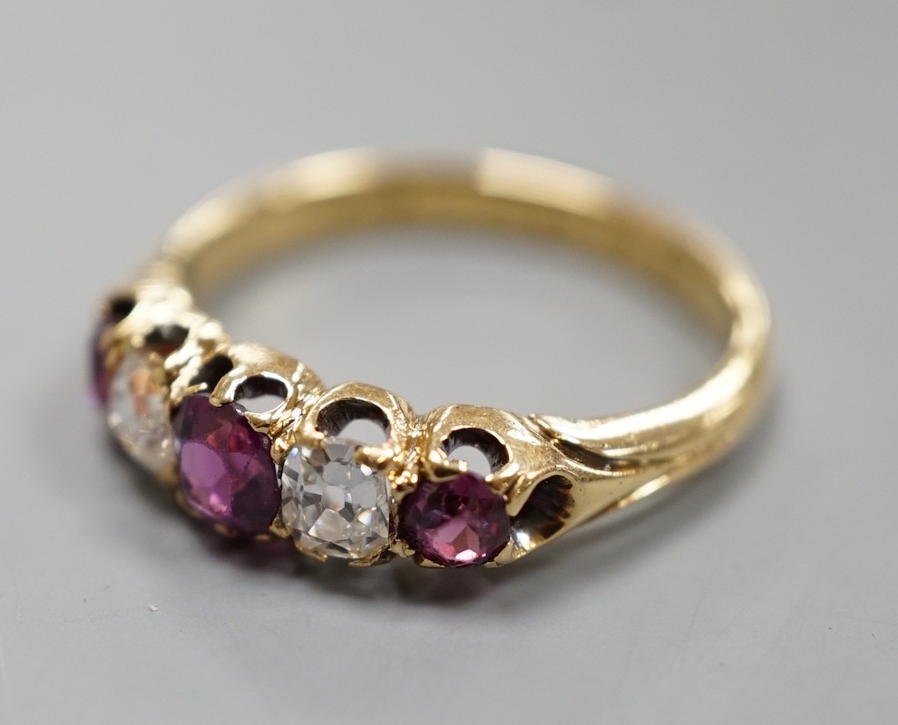 An 18ct gold, three stone ruby and two stone diamond set half hoop ring, size O, gross weight 3.7 grams.